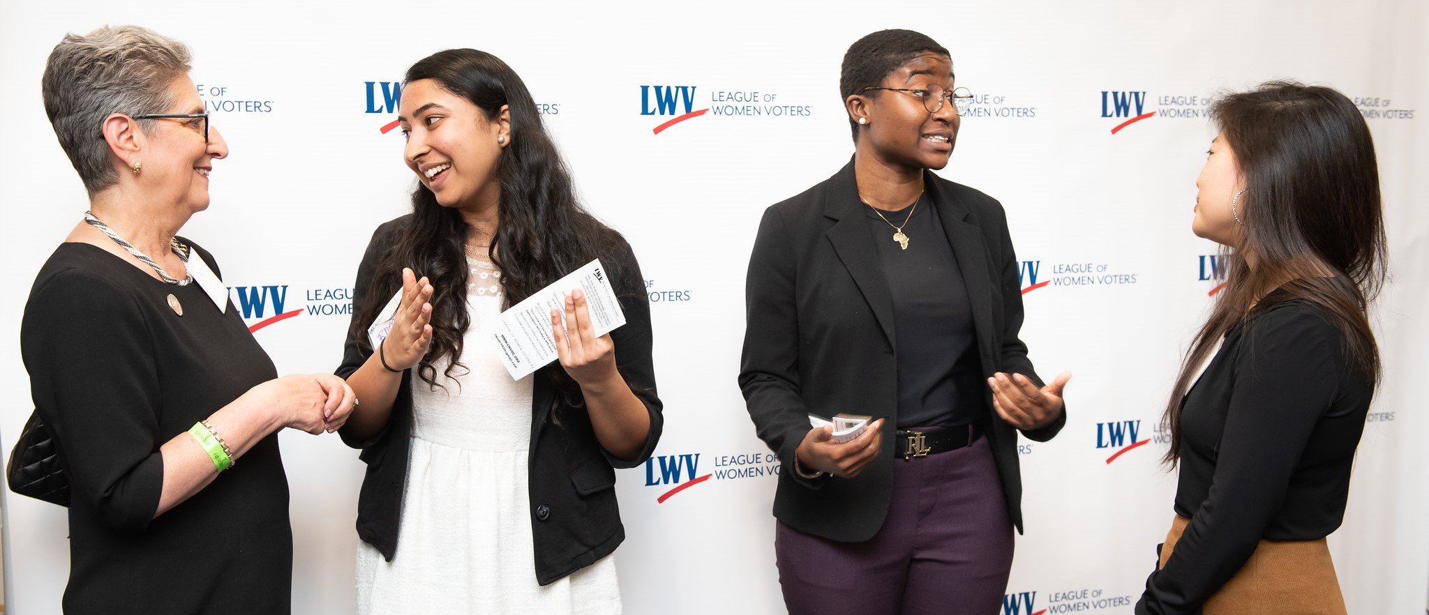 Four women chatting together in front of LWV logos background